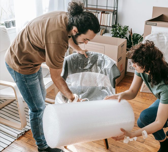 Two people are moving a large piece of furniture.