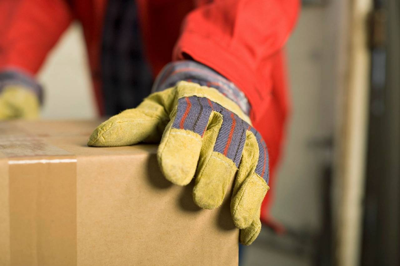 A person wearing gloves and holding onto boxes.