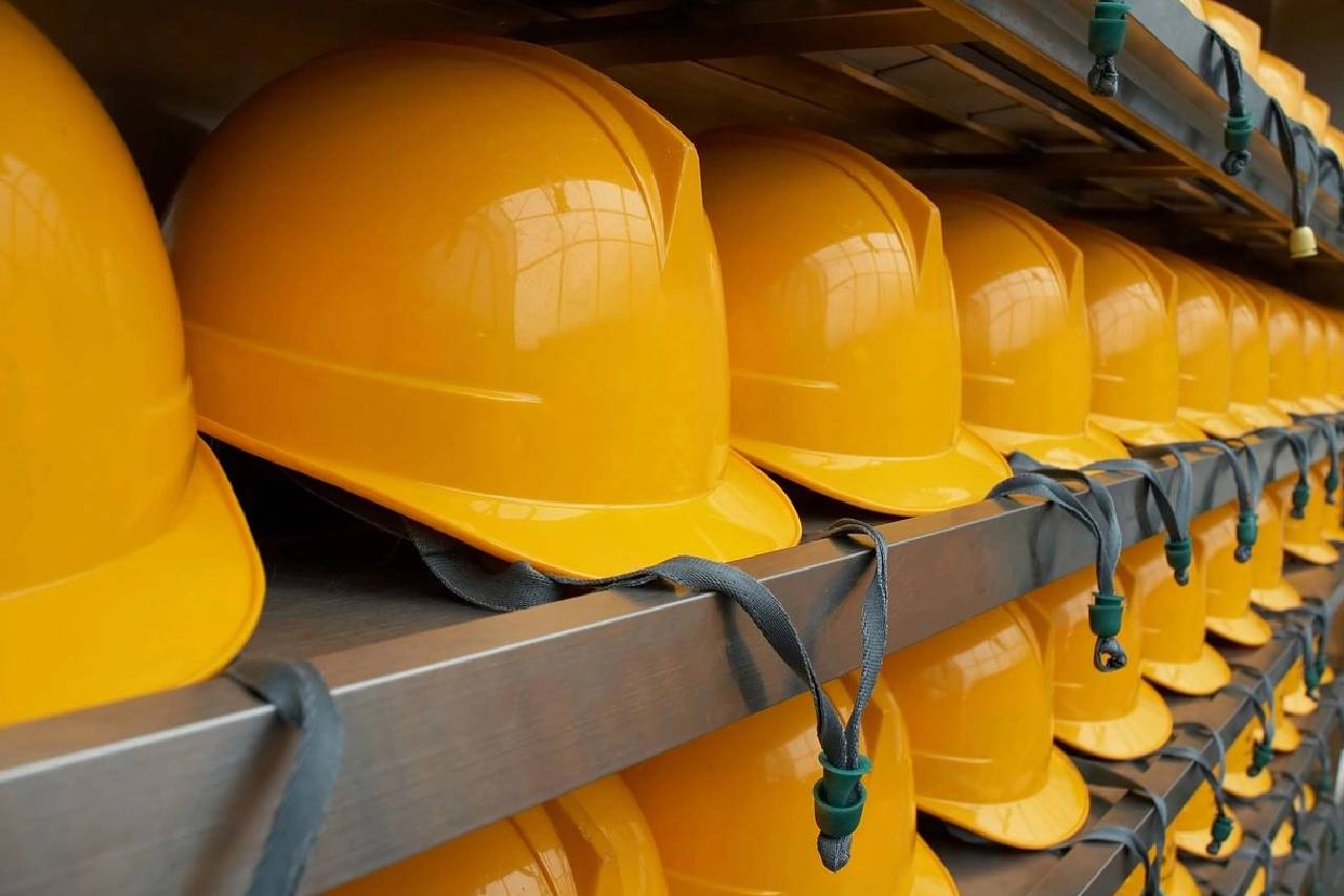 A row of yellow hard hats on top of shelves.