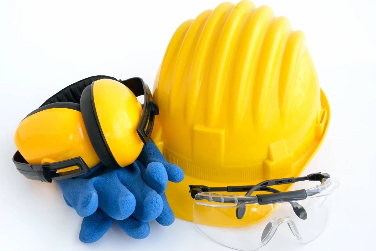 A yellow hard hat and goggles next to a pair of blue safety glasses.