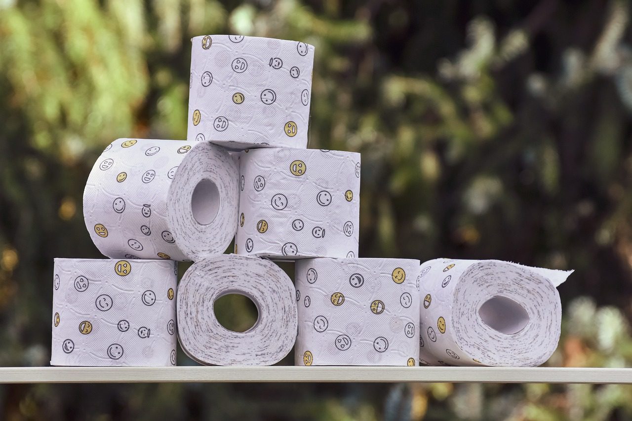 A pile of toilet paper sitting on top of a wooden shelf.